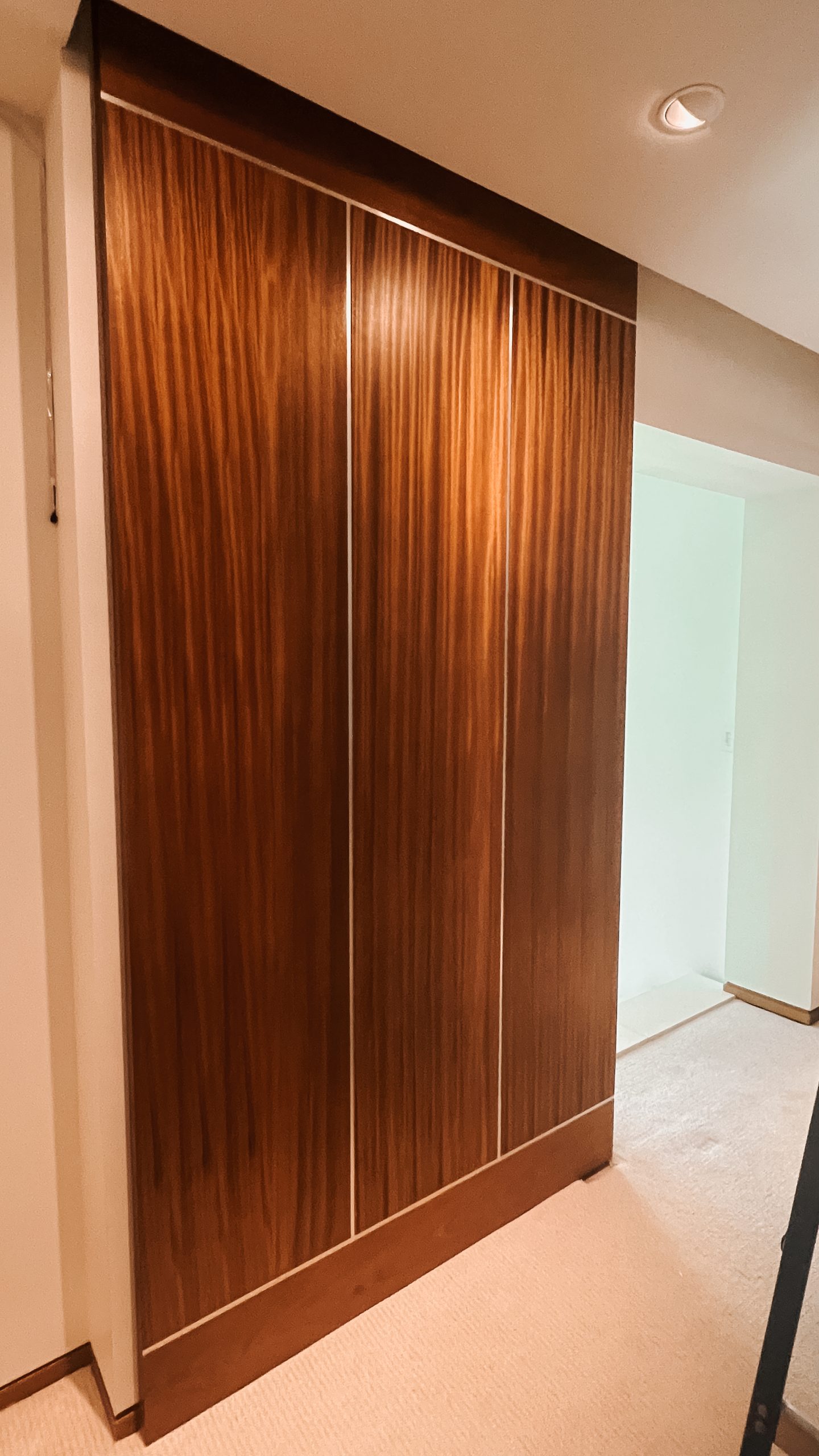 A massive ribbon striped mahogany and stainless steel sliding door