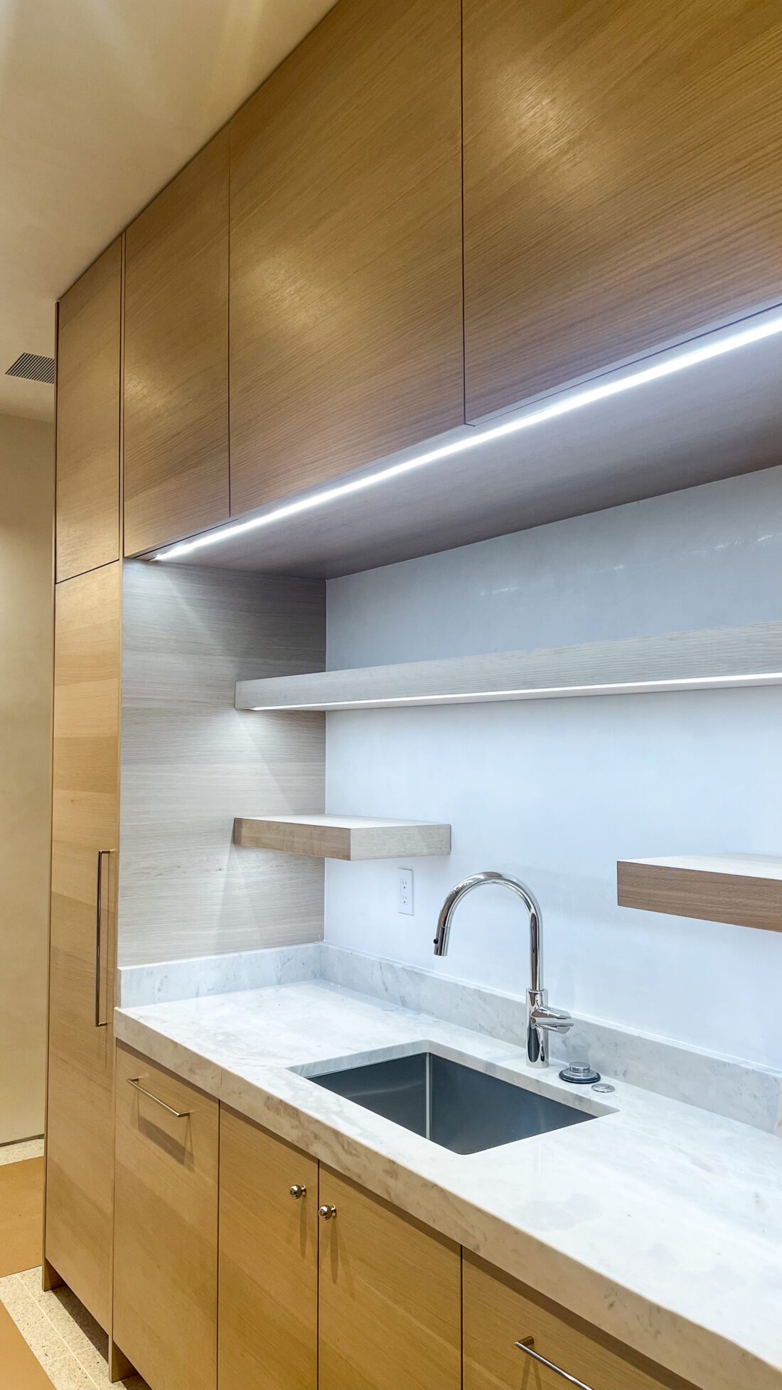 Integrated lighting design in marble and white oak cabinets by MDM Design Studio
