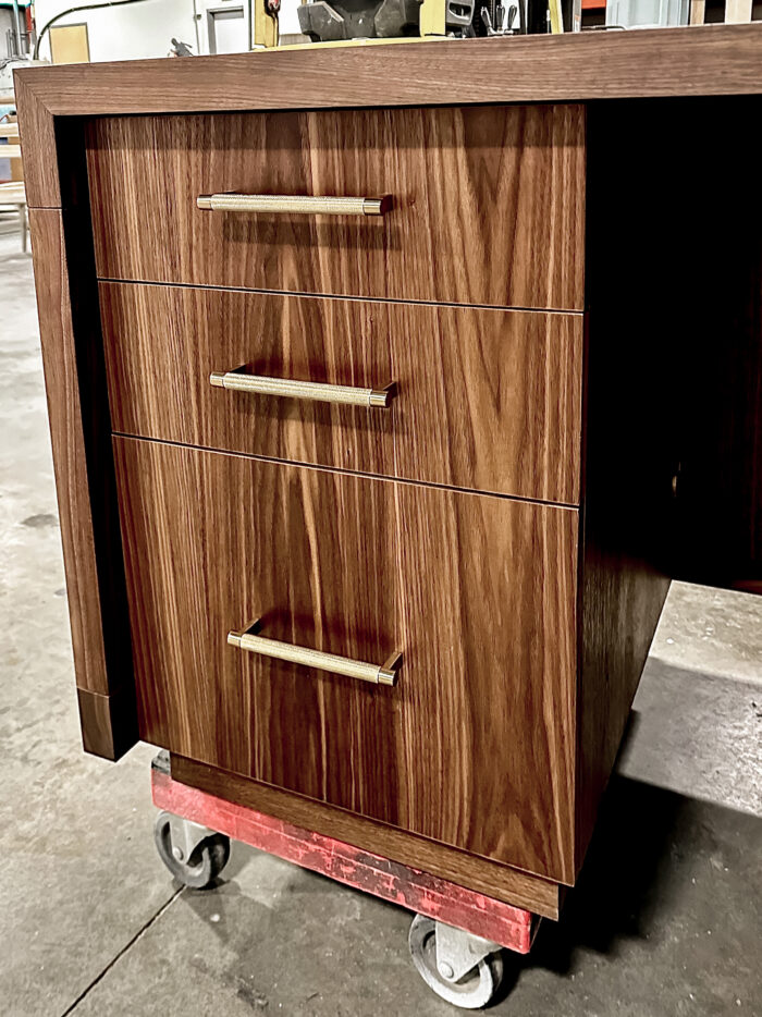 Top and side angle view of the desk, capturing its polished wood surface and angular craftsmanship.