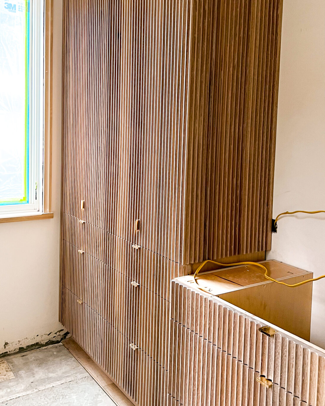 Tall fluted cabinet wall with vertical texture and brass handles.