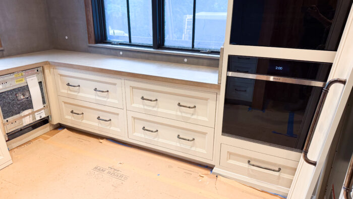 Corner kitchen with cream cabinets, bronze handles, and cast concrete countertop
