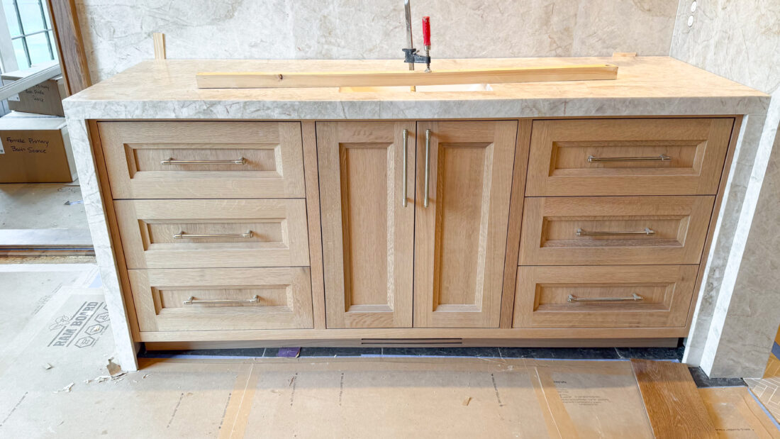Oak bathroom vanity with marble counter and backsplash surround