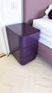 Custom high-gloss purple lacquer nightstand with curved, seamless design and push-to-open drawers.
