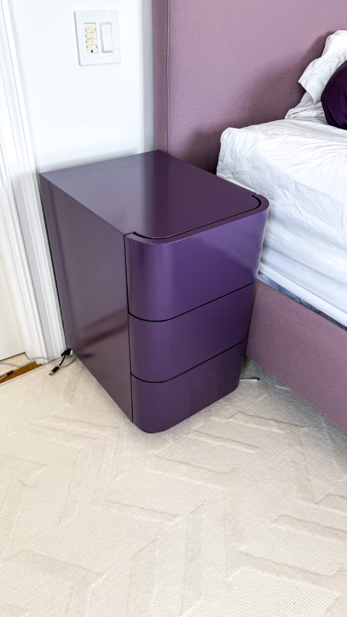 Custom high-gloss purple lacquer nightstand with curved, seamless design and push-to-open drawers.