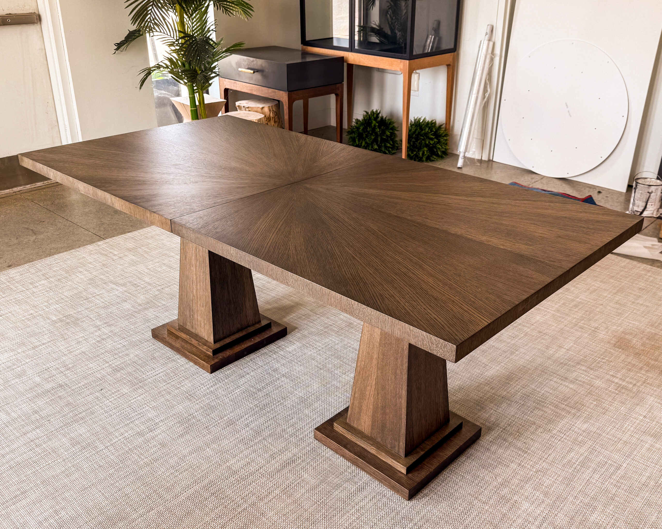 A timeless dining table design featuring a rich wood veneer top and strong plinth-style pedestal bases. Balanced proportions and clean geometry create a refined centerpiece for any dining space.